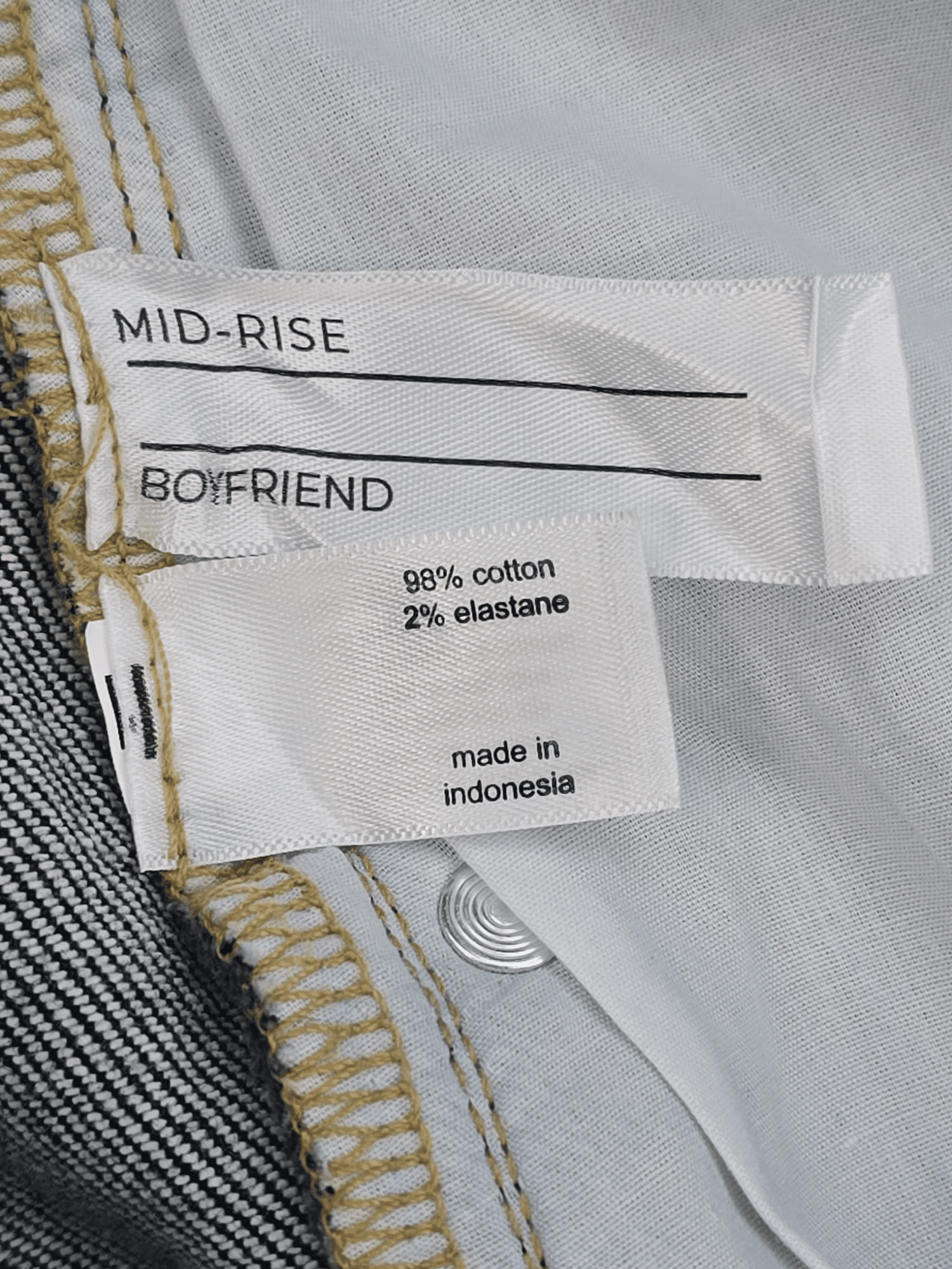 Close-up of material content and garment care tag on Lane Bryant women’s size 22 cropped jeans with plaid cuff