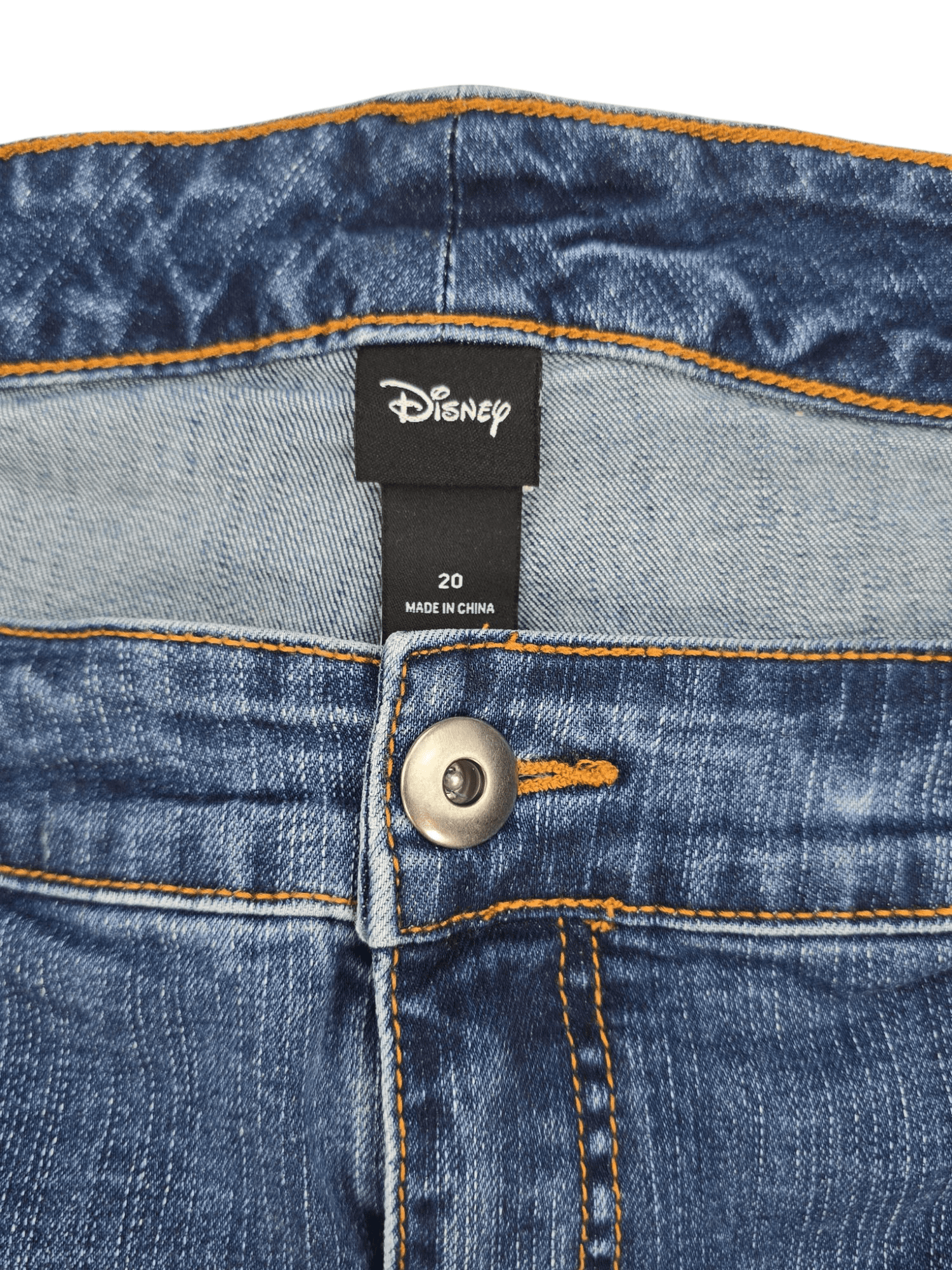 Close-up of Disney brand and size 20 tag on blue denim cropped jeans with Mickey Mouse patchwork