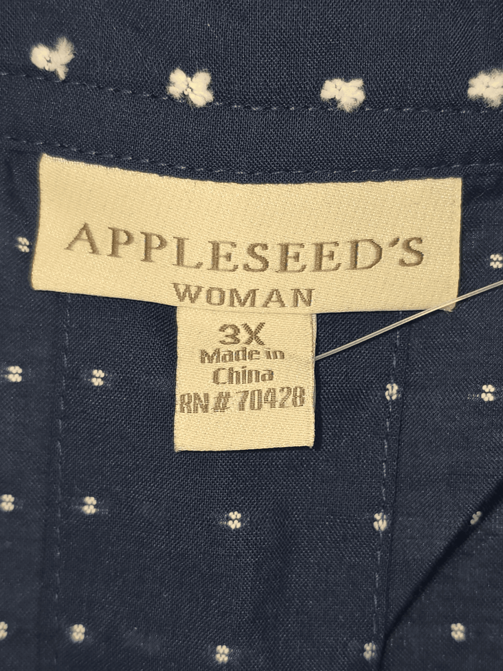 Close-up of Appleseed’s brand and 3X size tag on navy blue clip dot button-front top