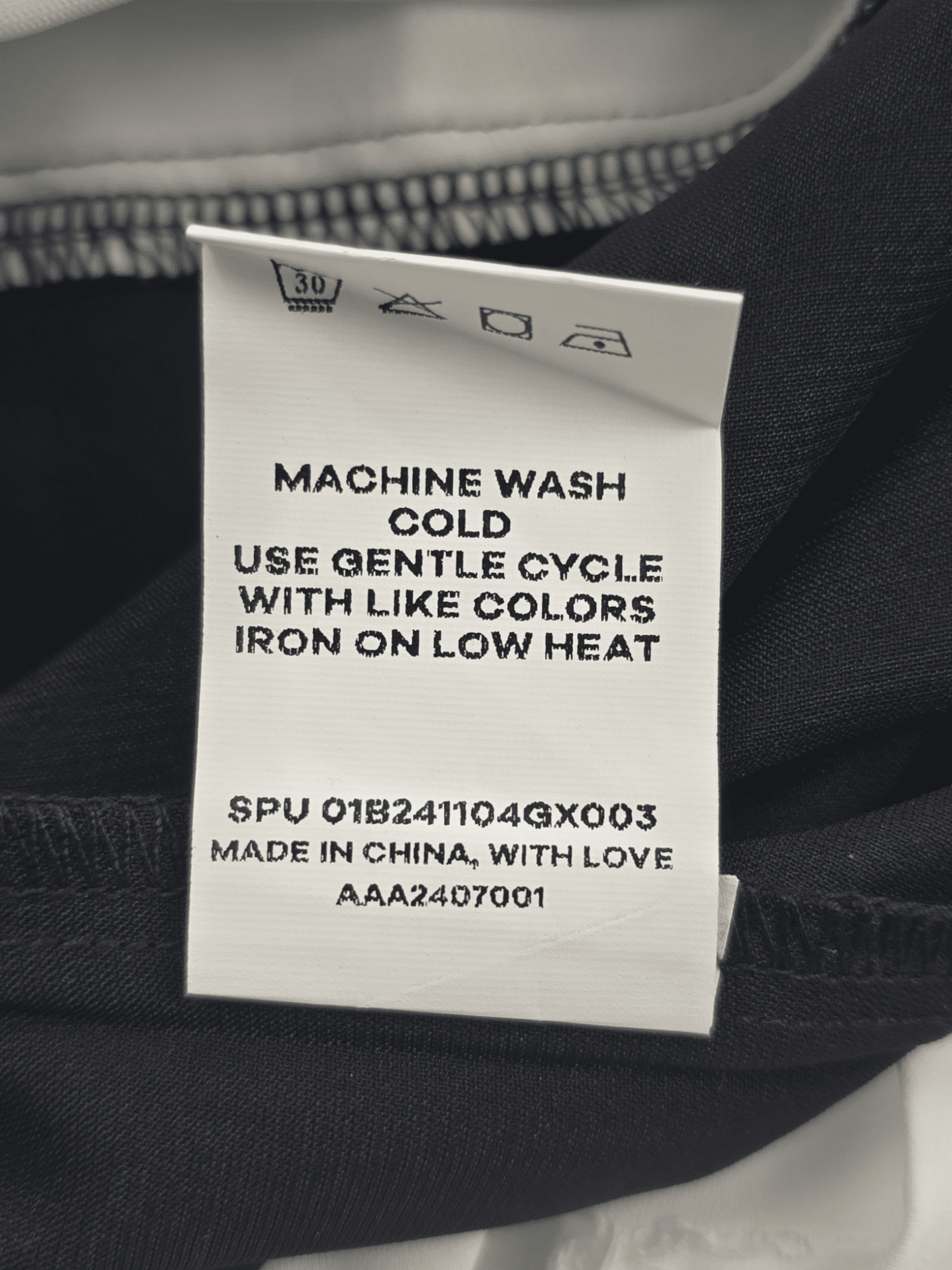 Close-up of material content and garment care tag on BloomChic women’s size 18/20 black and white layered-look pullover top