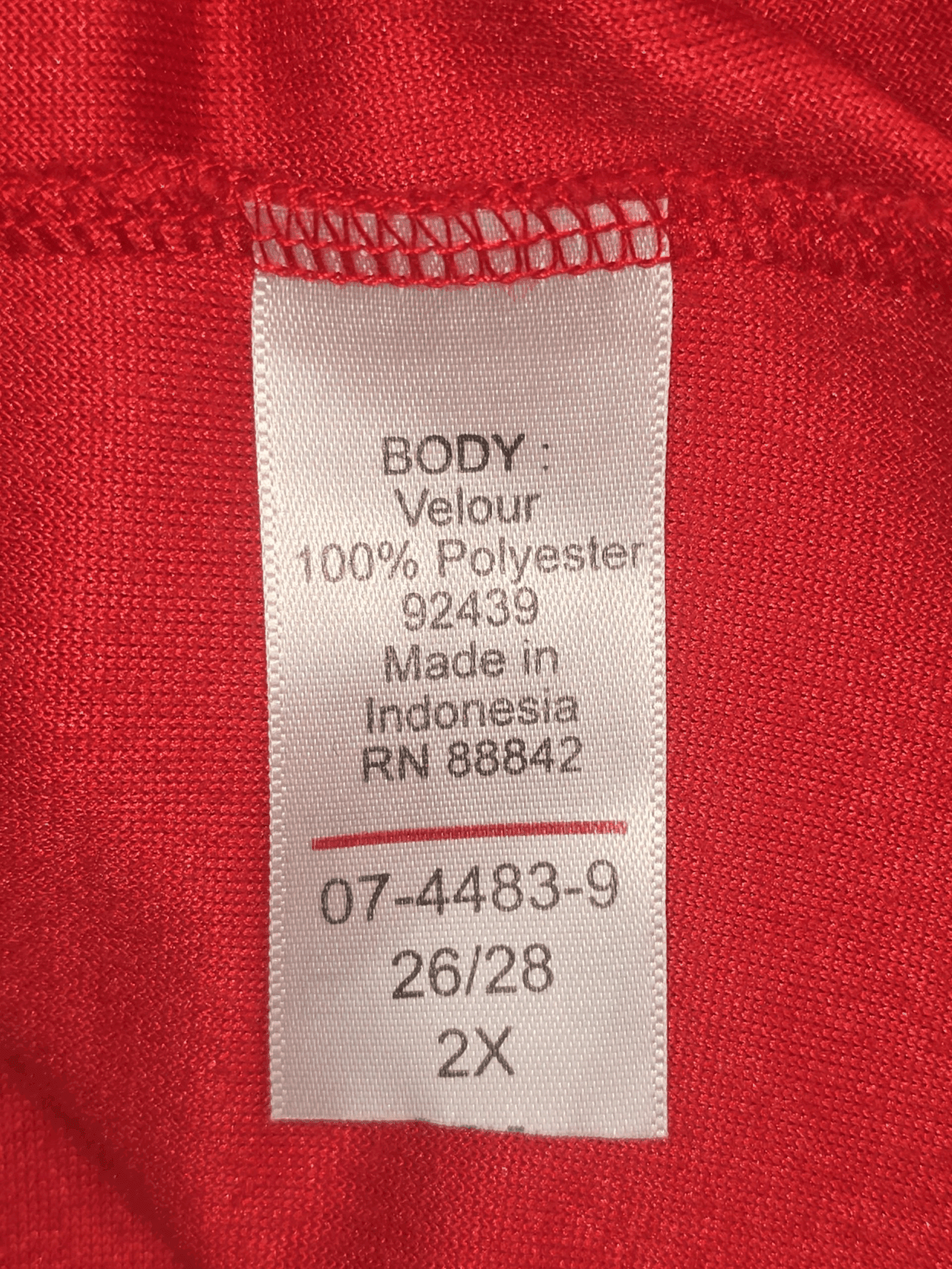 Close-up of material content and garment care tag on Woman Within women’s size 2X red velour pullover top