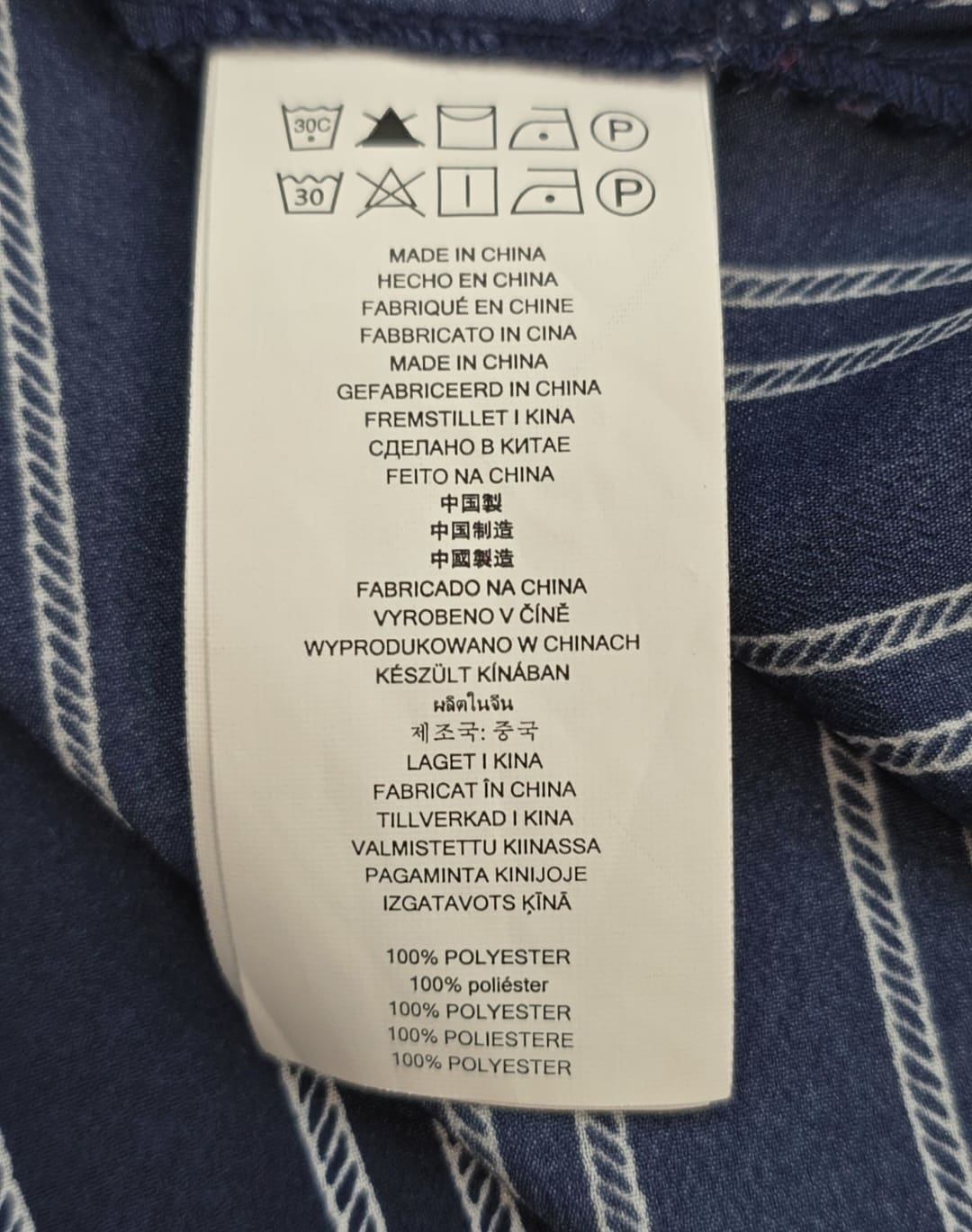 Close-up of material content and garment care tag on Michael Kors women’s size 2X navy blue gold-zip shirt