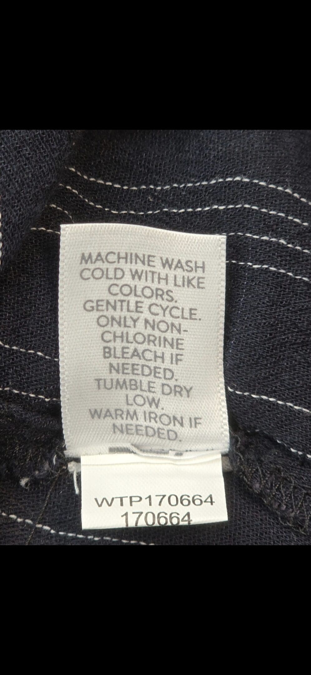 Close-up of material content and garment care tag on Michael Kors women’s size 2X navy blue gold-zip shirt