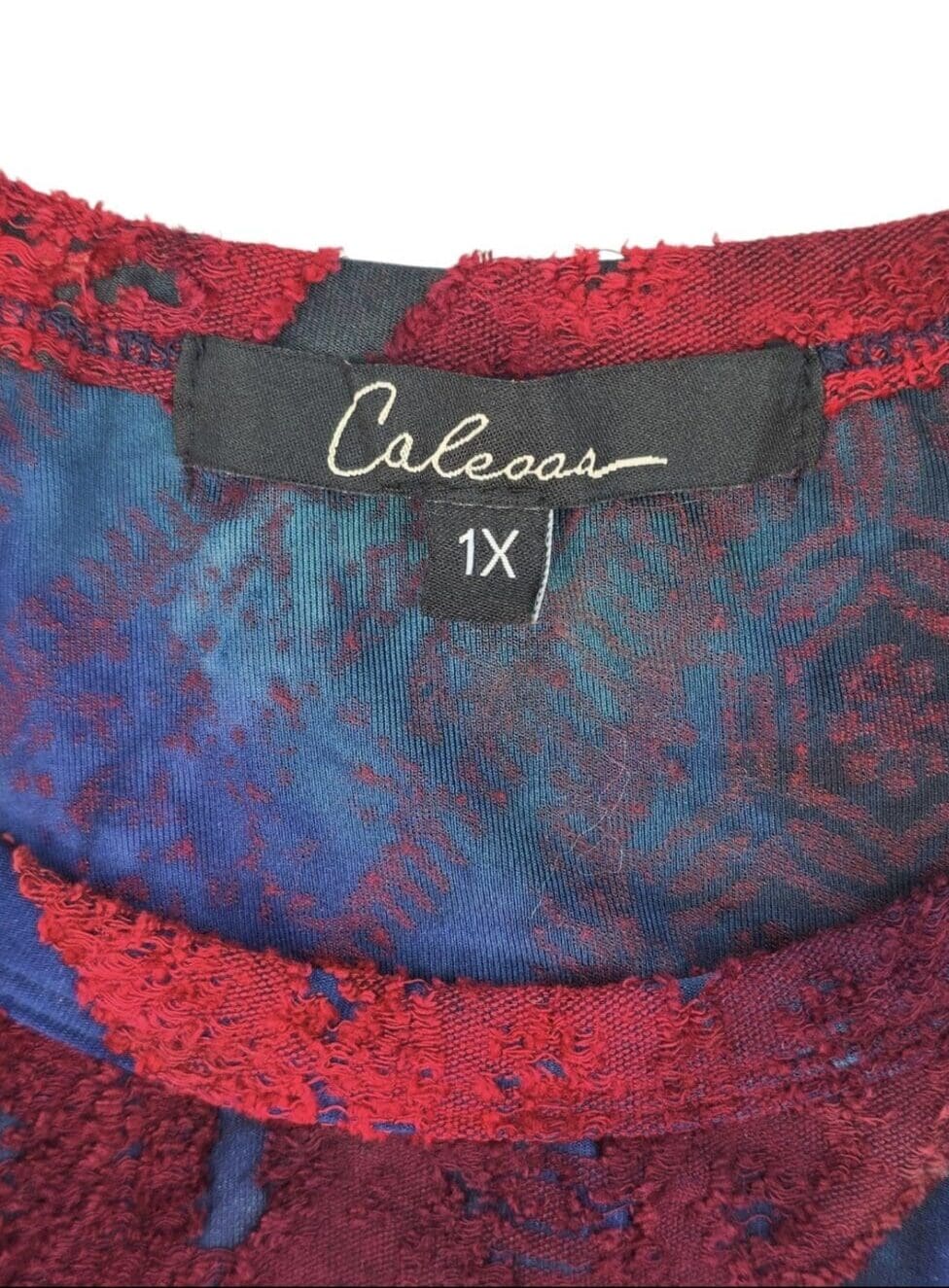 Close-up of Calessa brand and 1X size tag on multicolor textured pullover top
