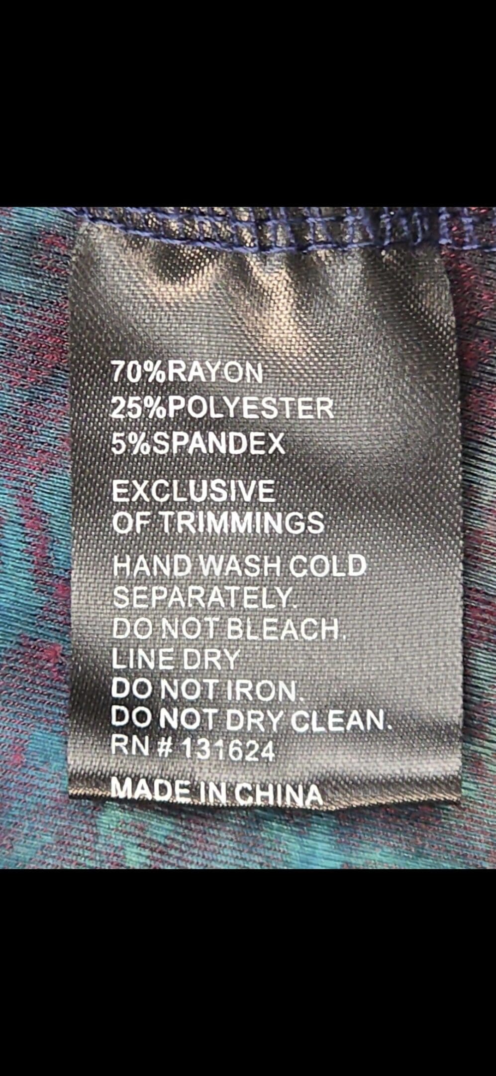Close-up of Calessa brand and 1X size tag on multicolor textured pullover top
