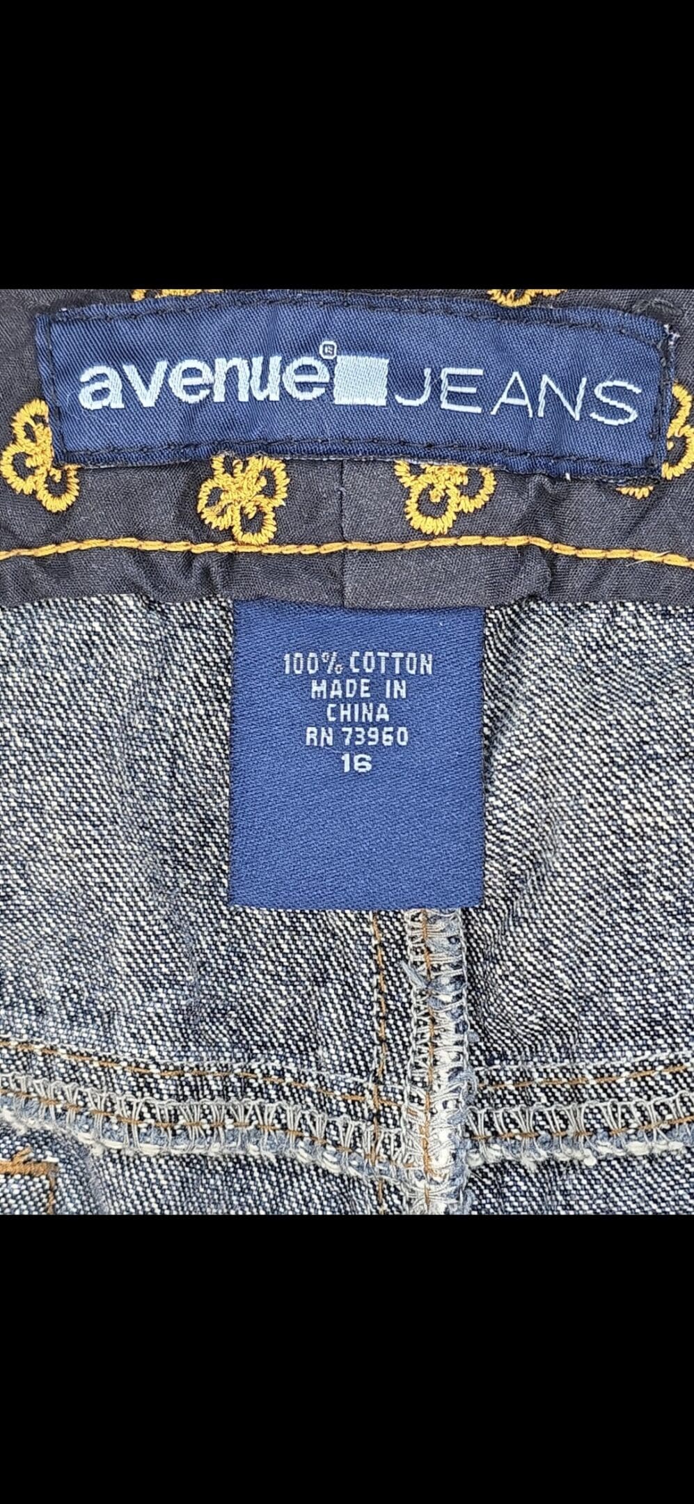 Close-up of material content and garment care tag on Avenue women’s size 16 blue denim capris with folded cuffs