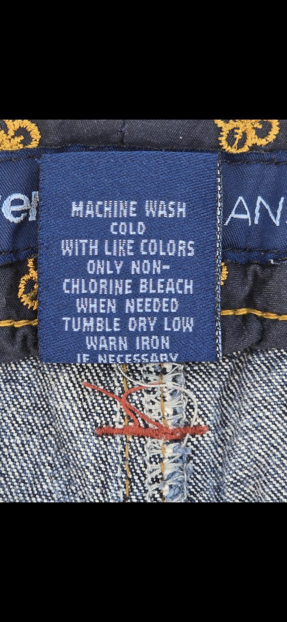 Close-up of material content and garment care tag on Avenue women’s size 16 blue denim capris with folded cuffs