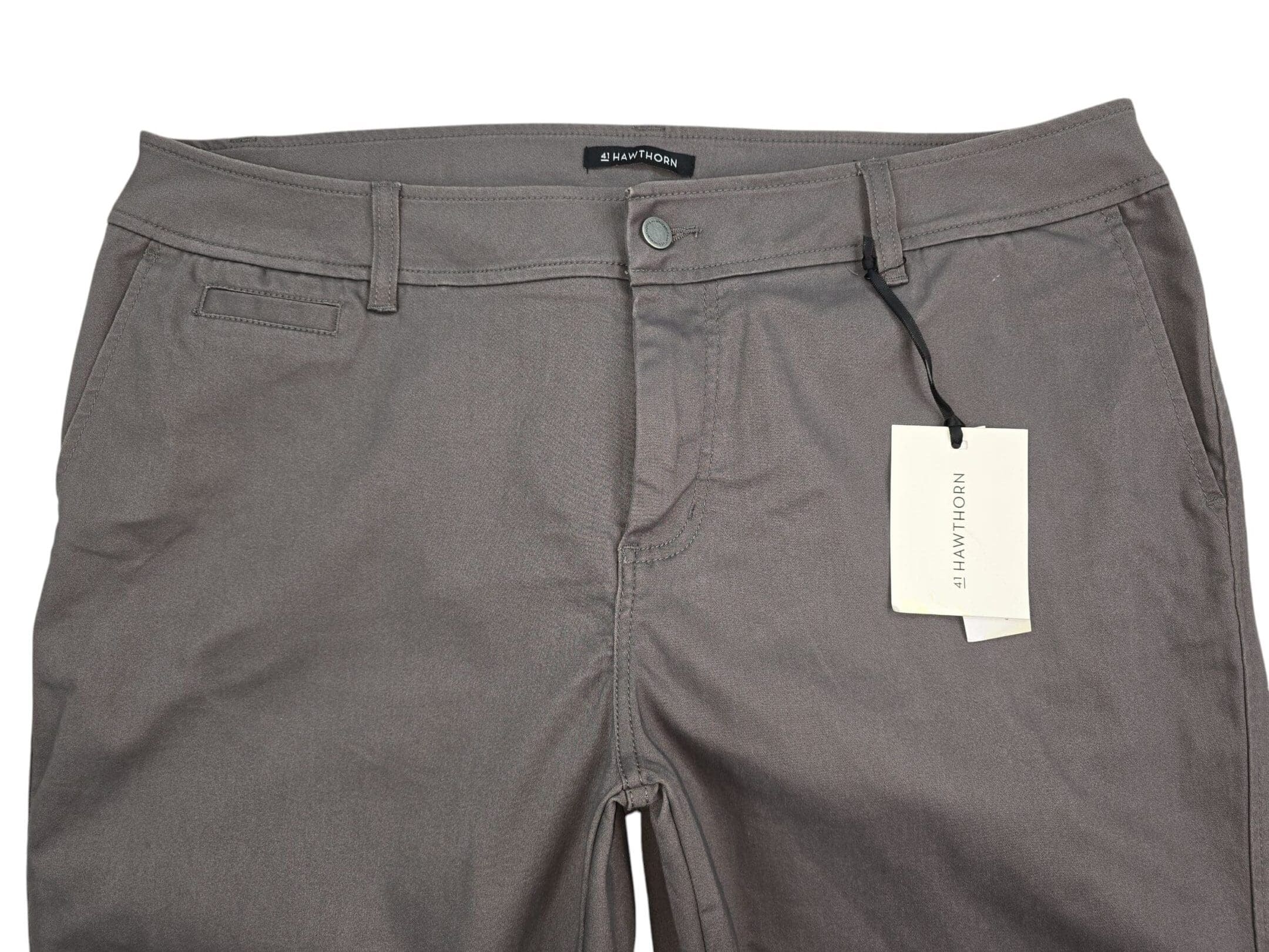 Close-up of gray pants with button and tag.
